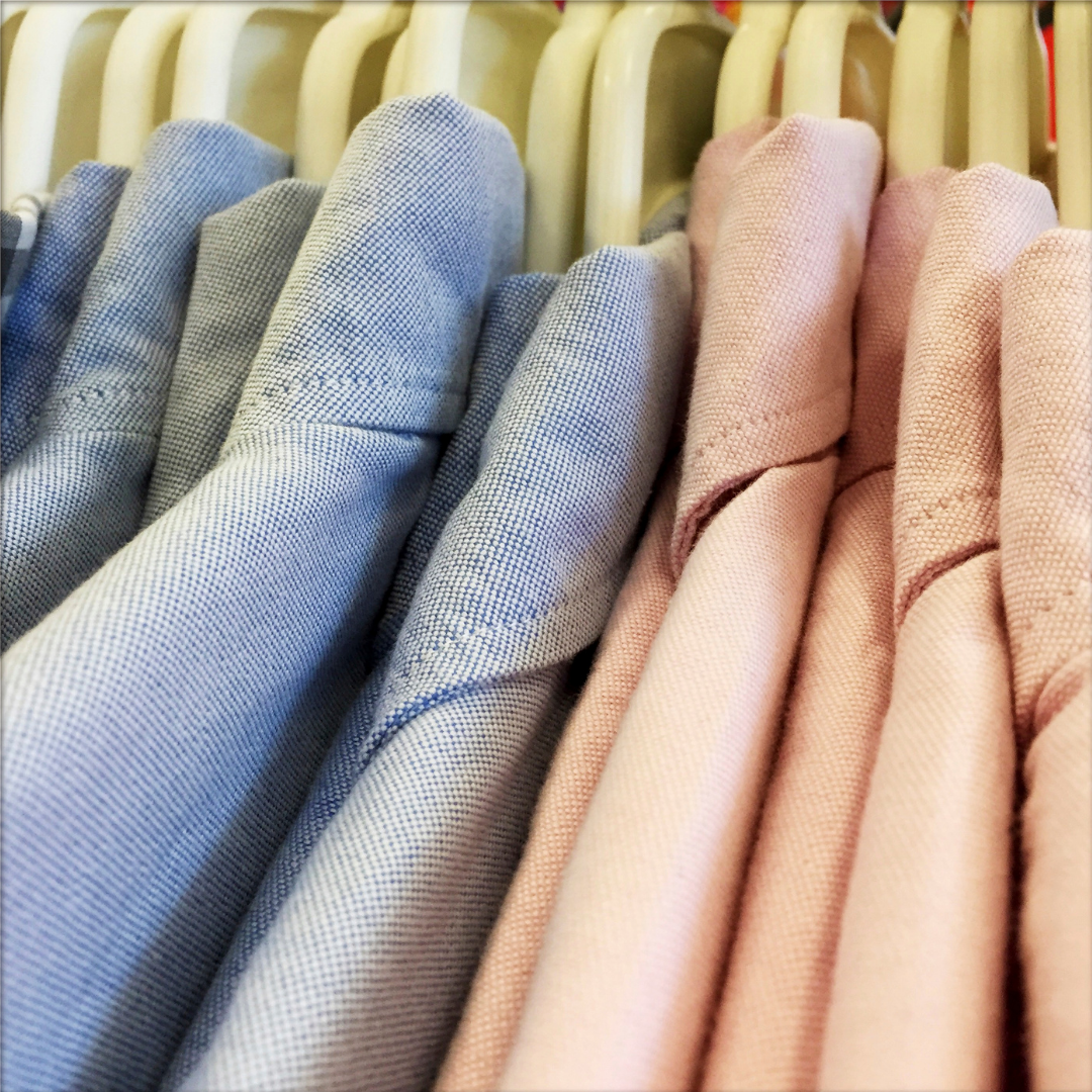 close up of blue and pink men's overshirts on hangers  